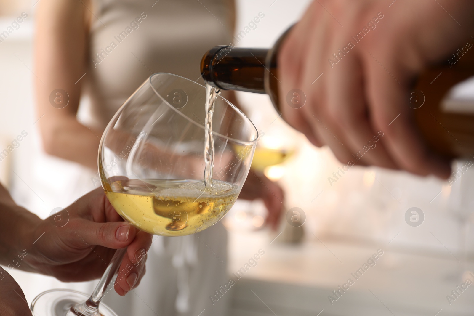 Photo of Man pouring wine into woman`s glass indoors, selective focus