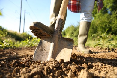 Farmer digging soil with shovel on sunny day, closeup