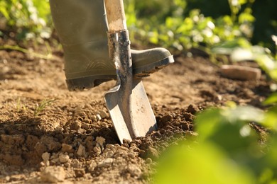 Farmer digging soil with shovel on sunny day, closeup