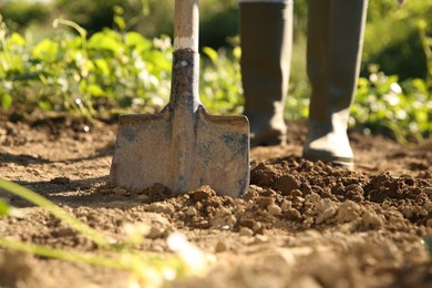 Farmer digging soil with shovel on sunny day, closeup