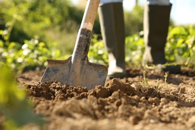 Farmer digging soil with shovel on sunny day, closeup