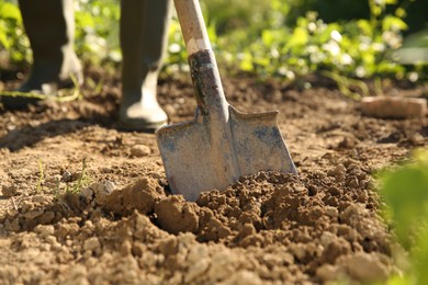 Farmer digging soil with shovel on sunny day, closeup