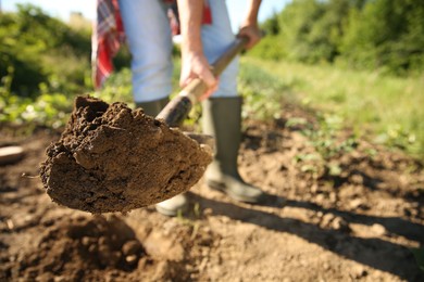 Farmer digging soil with shovel on sunny day, closeup