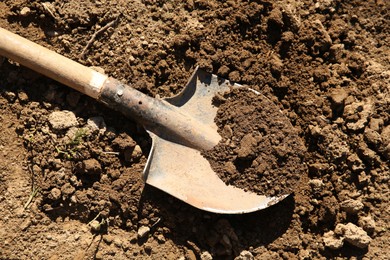 Photo of One shovel with soil on ground on sunny day, top view. Gardening season