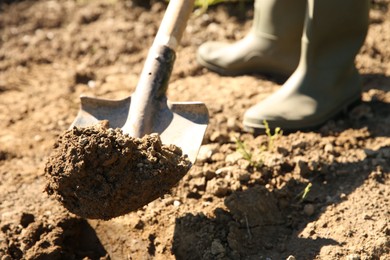 Farmer digging soil with shovel on sunny day, closeup