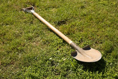 One rusty shovel on green grass. Gardening season