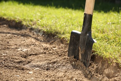 One shovel sticking out of ground on sunny day, space for text. Gardening season