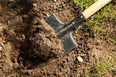 Photo of One shovel with soil on ground on sunny day, top view. Gardening season