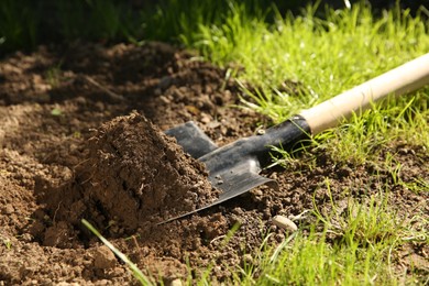 Photo of One shovel with soil on ground on sunny day. Gardening season