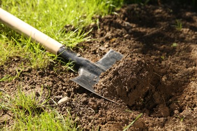 Photo of One shovel with soil on ground on sunny day. Gardening season