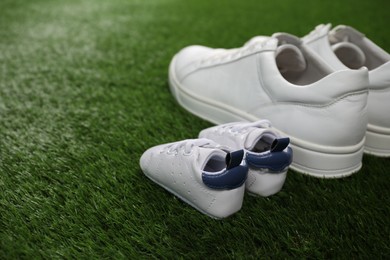 Big and small shoes on green grass, space for text