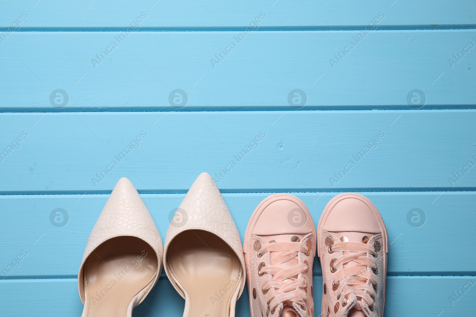 Photo of Big and small shoes on light blue wooden table, top view. Space for text