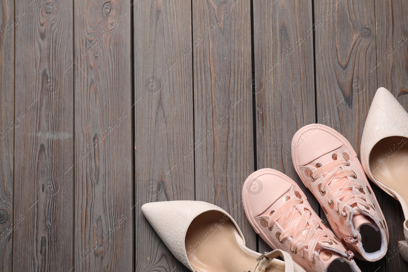 Photo of Big and small shoes on wooden table, top view. Space for text