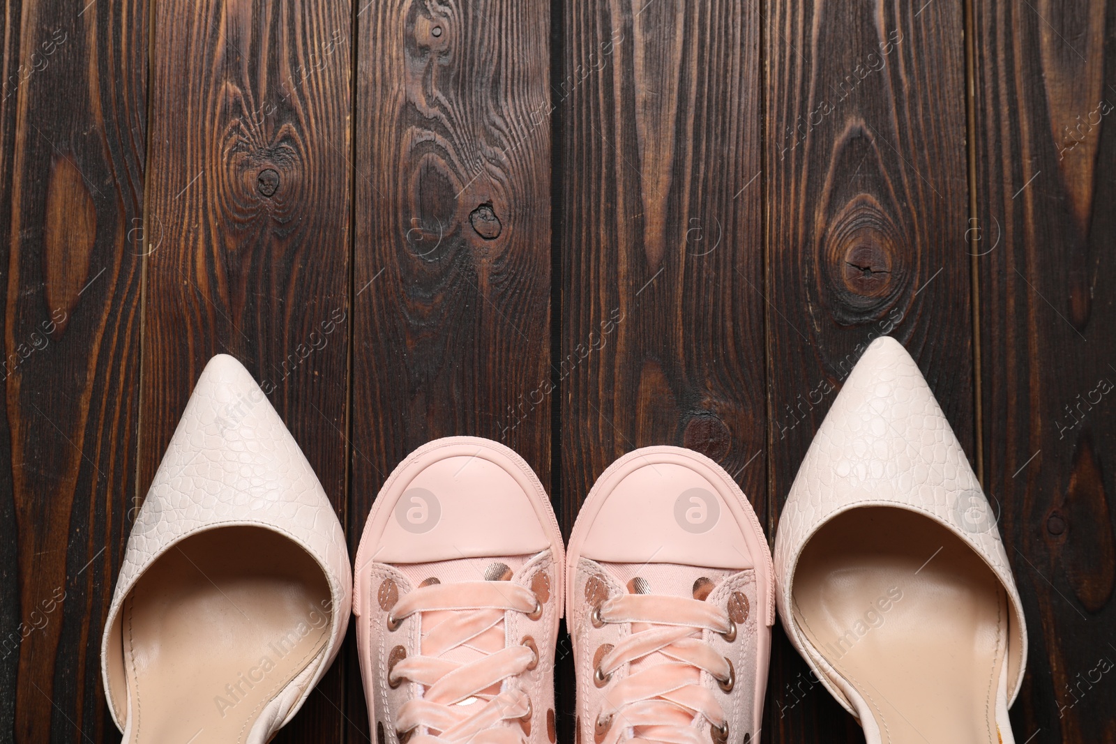 Photo of Big and small shoes on wooden table, top view. Space for text