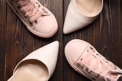 Photo of Big and small shoes on wooden table, flat lay