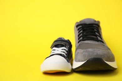 Big and small shoes on yellow background, space for text