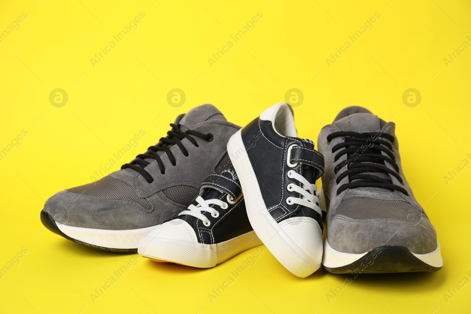 Photo of Big and small shoes on yellow background