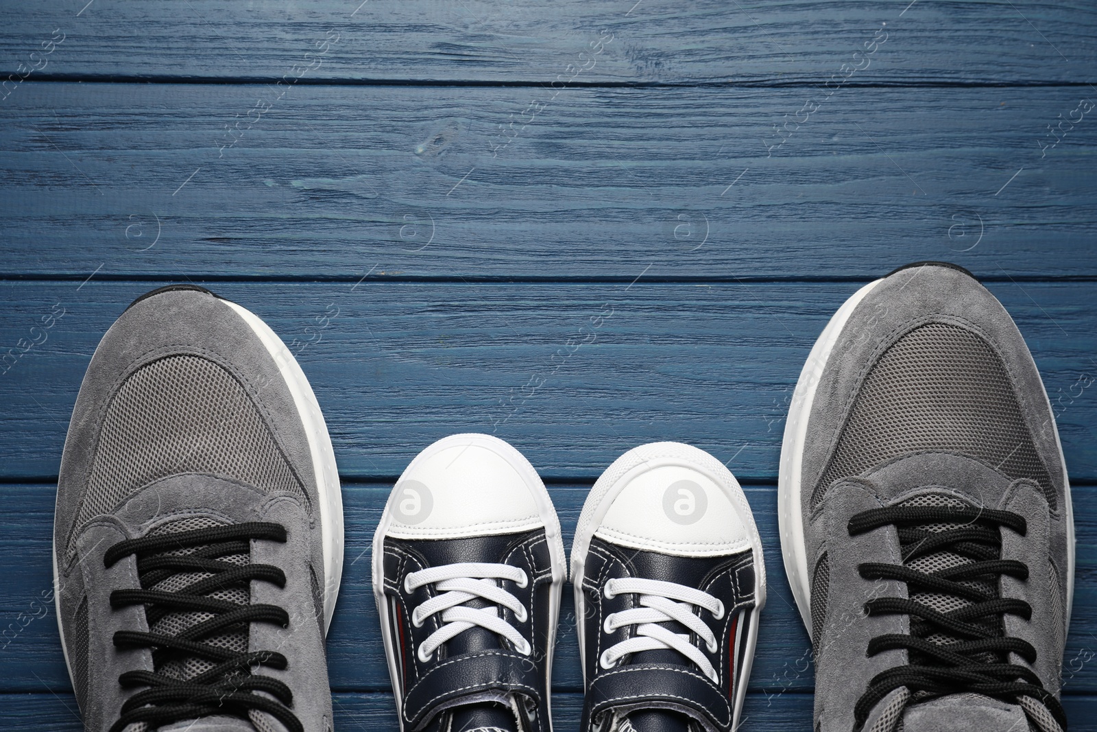 Photo of Big and small shoes on blue wooden table, top view. Space for text