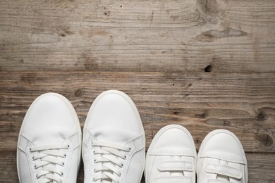 Big and small shoes on wooden table, top view. Space for text