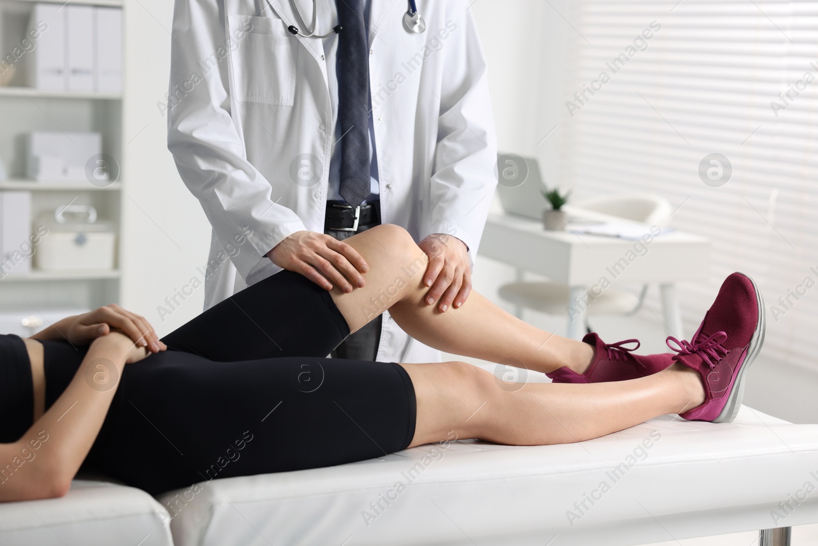 Photo of Sports injury. Doctor examining patient's leg in hospital, closeup