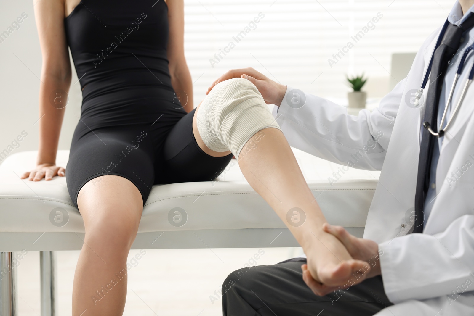 Photo of Sports injury. Doctor examining patient's knee in hospital, closeup