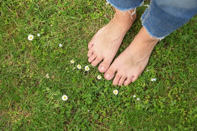 Photo of Woman walking barefoot on green grass outdoors, top view. Space for text