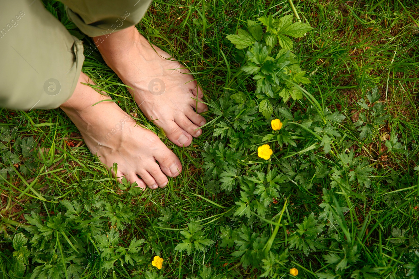 Photo of Woman walking barefoot on green grass outdoors, top view. Space for text