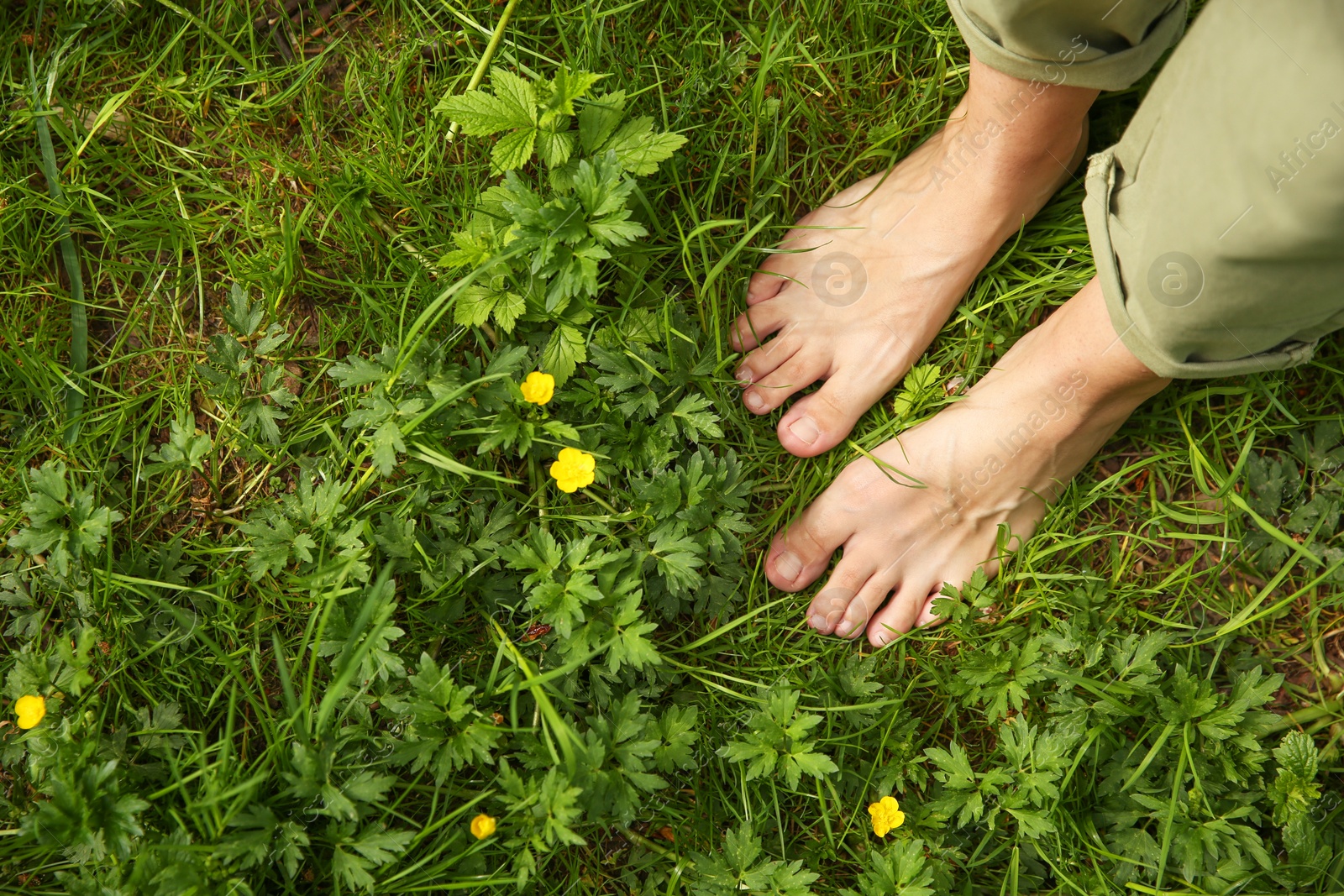 Photo of Woman walking barefoot on green grass outdoors, top view. Space for text