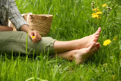 Photo of Woman sitting barefoot on green grass outdoors, closeup