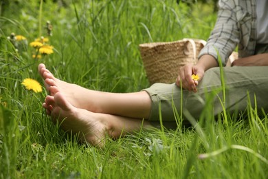 Woman sitting barefoot on green grass outdoors, closeup