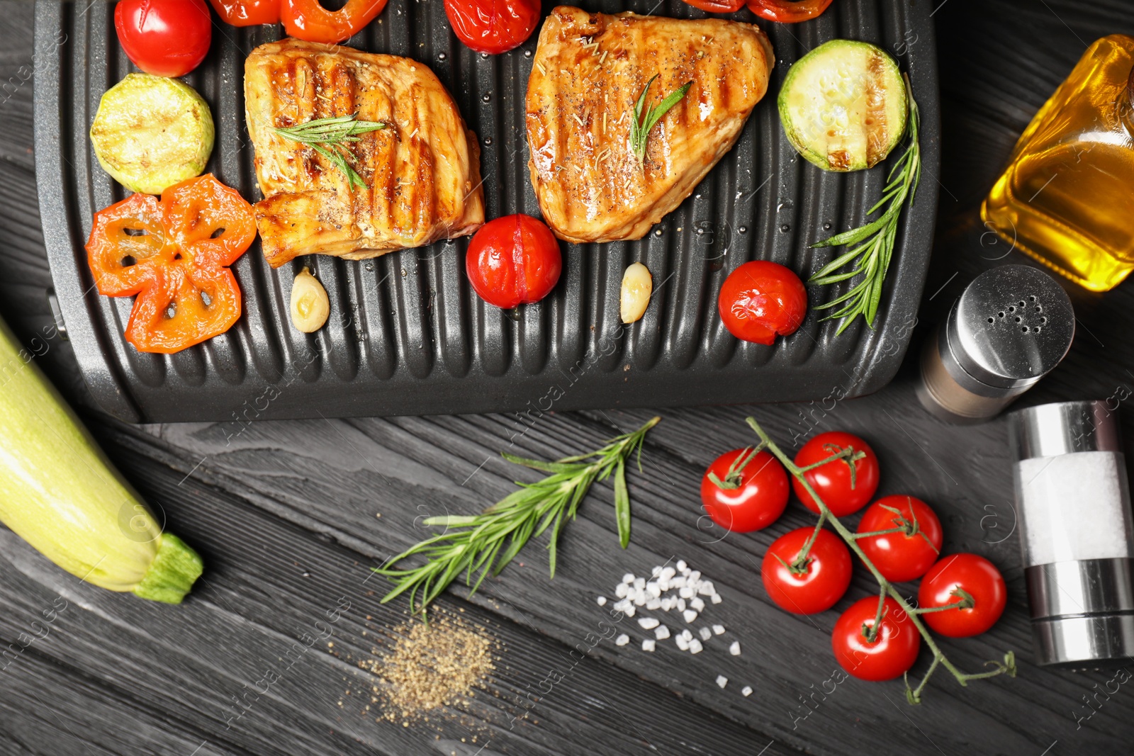 Photo of Flat lay composition with electric grill and different products on black wooden table