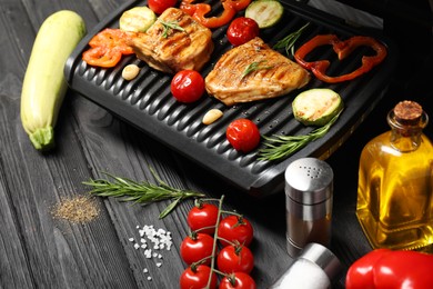 Photo of Electric grill with different products on black wooden table