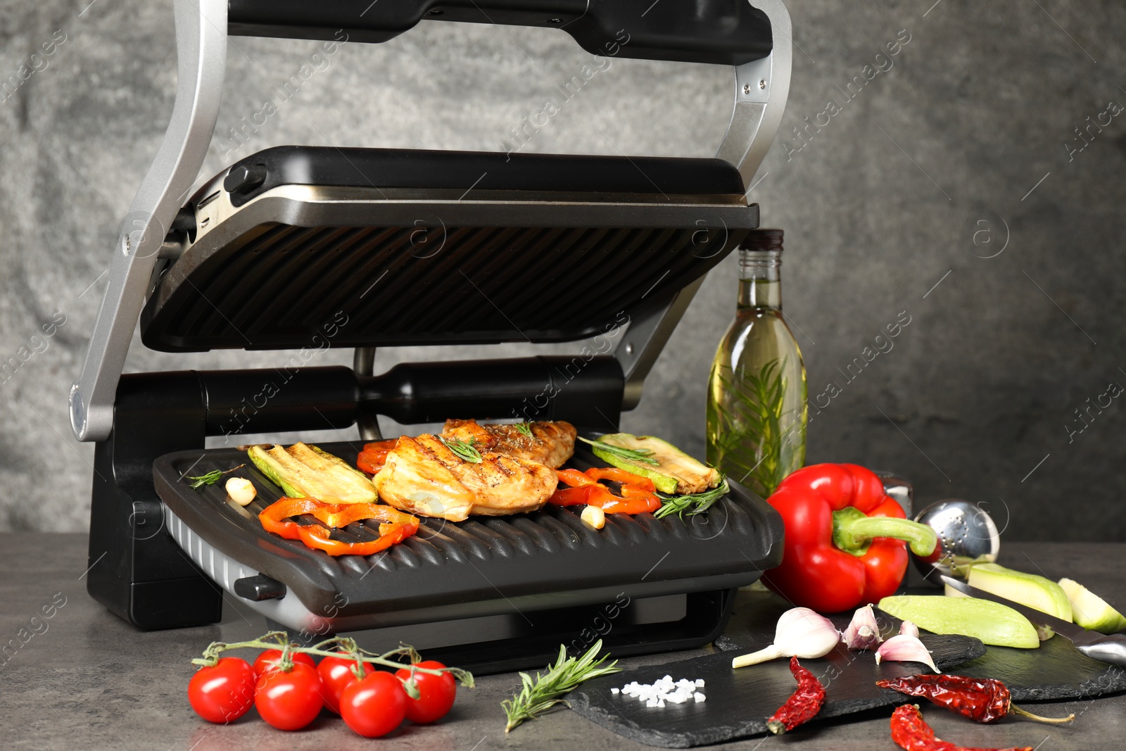 Photo of Electric grill with different products on grey textured table