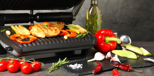 Photo of Electric grill with different products on grey textured table