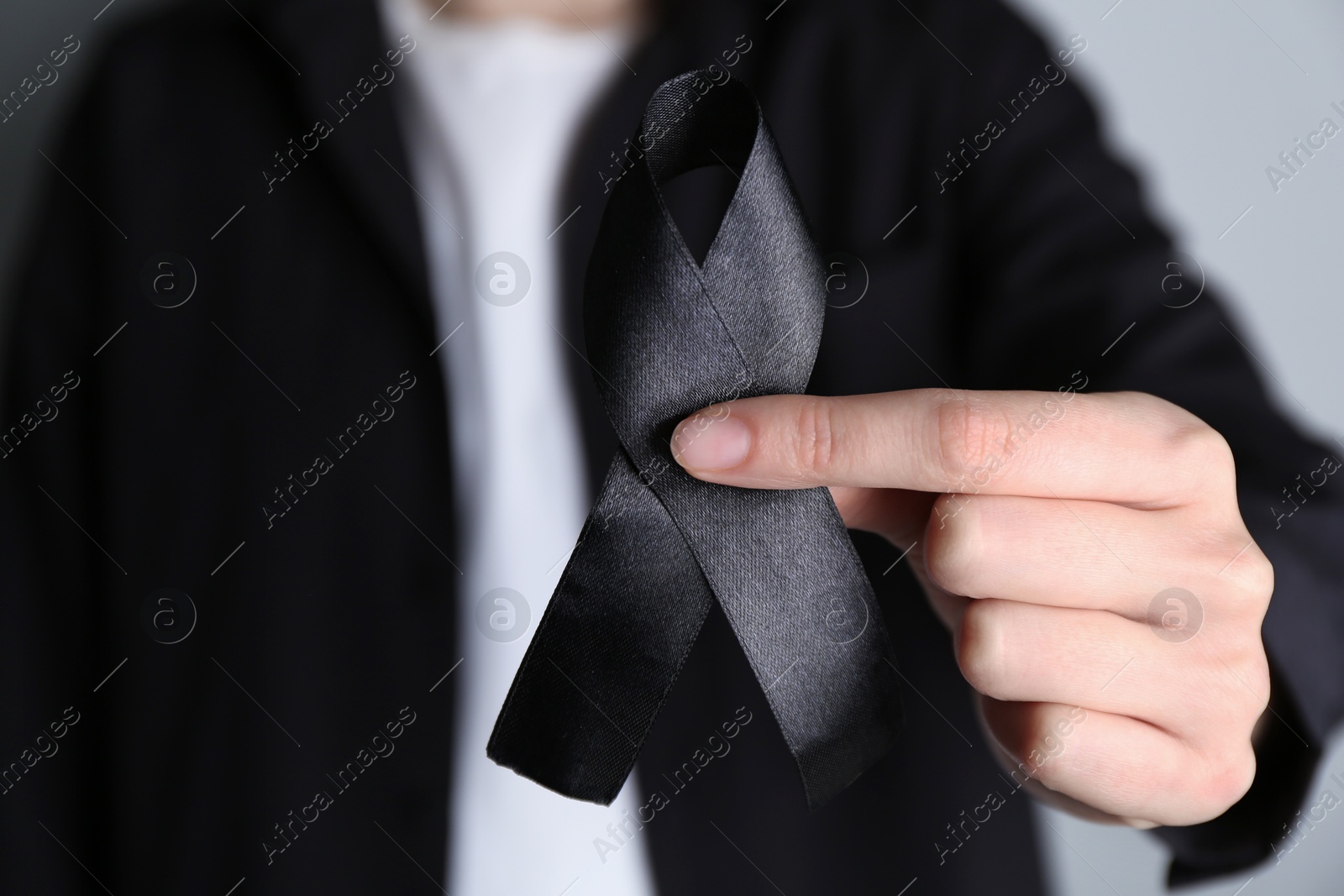Photo of Woman holding black awareness ribbon, closeup view