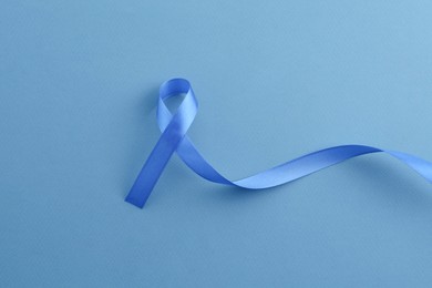 Photo of Blue awareness ribbon on color background, top view
