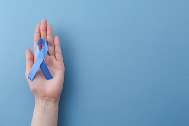 Photo of Woman with blue awareness ribbon on color background, top view. Space for text