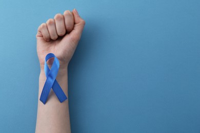 Photo of Woman with blue awareness ribbon on color background, top view. Space for text