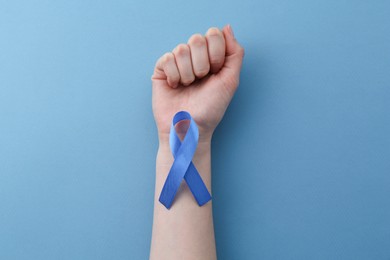 Photo of Woman with blue awareness ribbon on color background, top view
