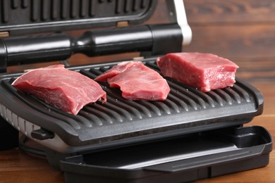 Electric grill with raw meat on table, closeup