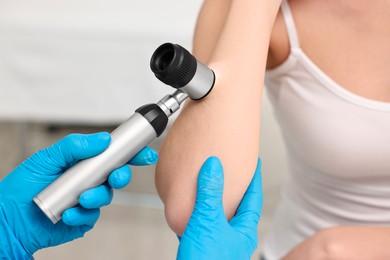 Photo of Dermatologist with dermatoscope examining patient in clinic, closeup