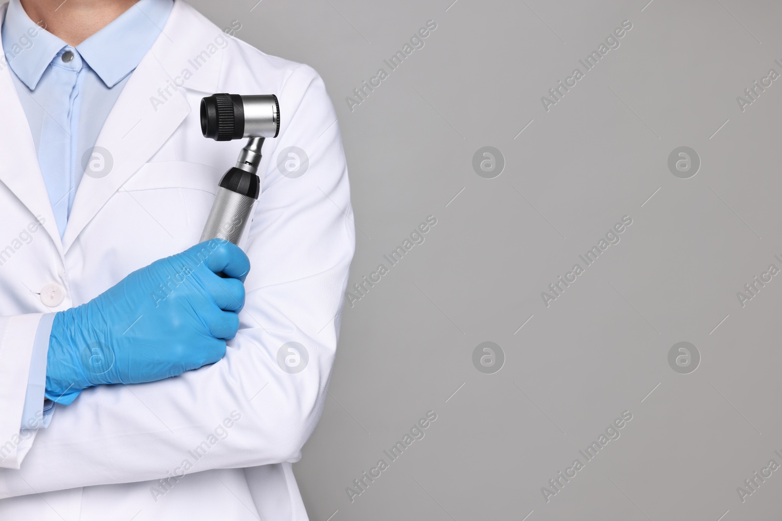 Photo of Dermatologist with dermatoscope on grey background, closeup. Space for text