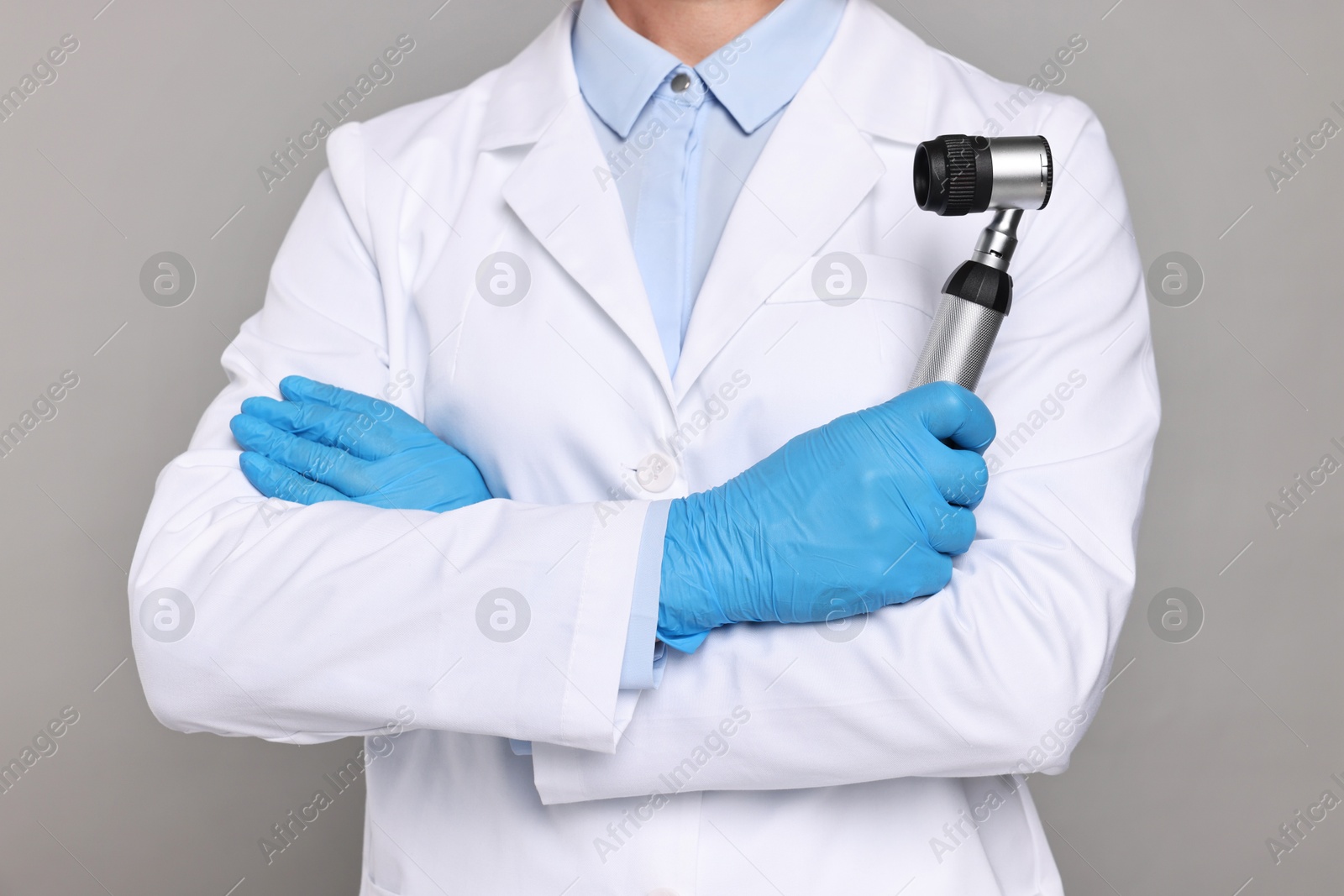 Photo of Dermatologist with dermatoscope on grey background, closeup