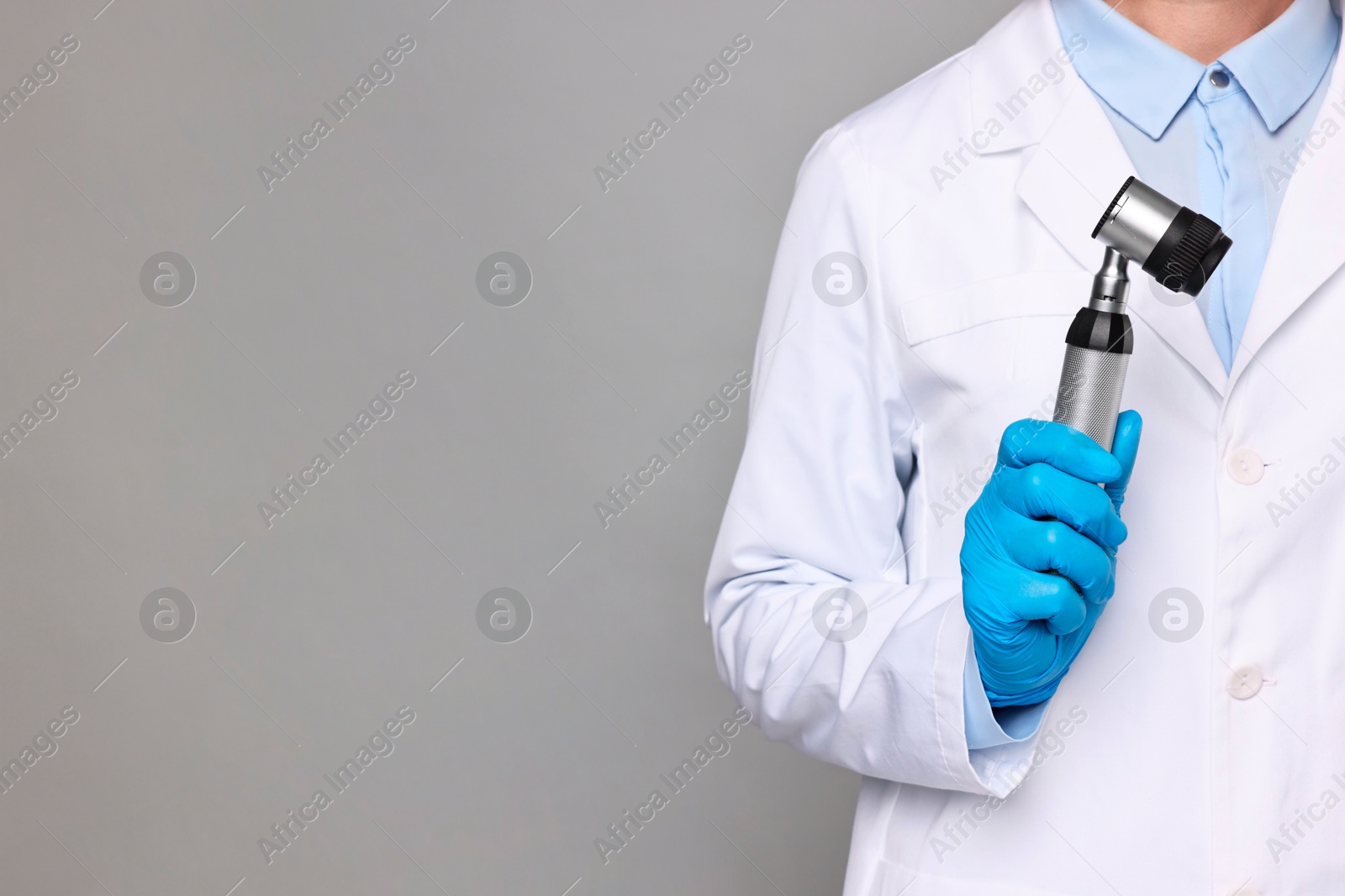 Photo of Dermatologist with dermatoscope on grey background, closeup. Space for text