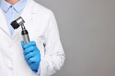 Dermatologist with dermatoscope on grey background, closeup. Space for text