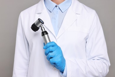 Dermatologist with dermatoscope on grey background, closeup