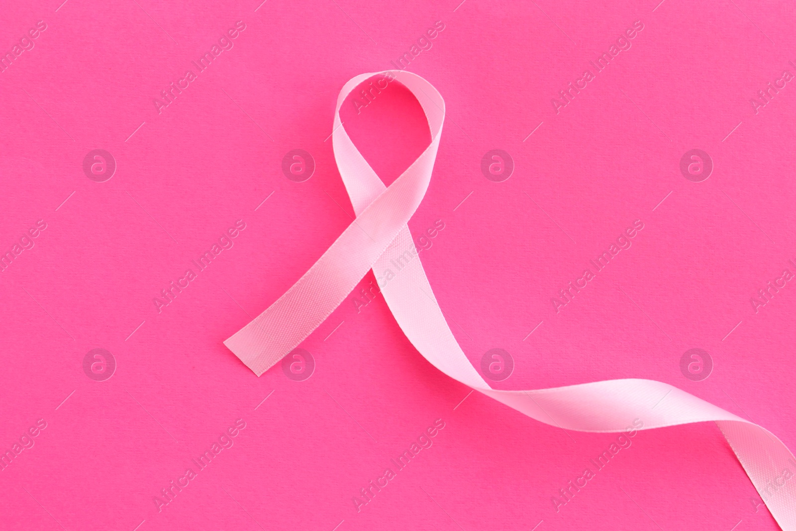 Photo of Awareness ribbon on pink background, top view. Space for text
