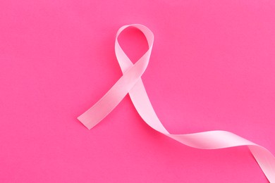 Awareness ribbon on pink background, top view. Space for text