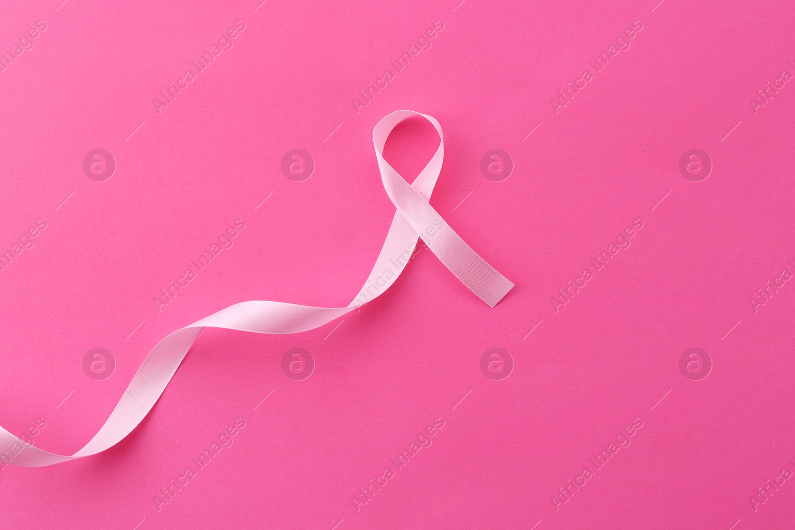 Photo of Awareness ribbon on pink background, top view. Space for text