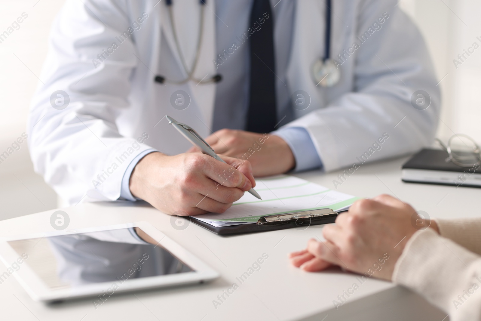 Photo of Professional doctor working with patient at white table in hospital, closeup